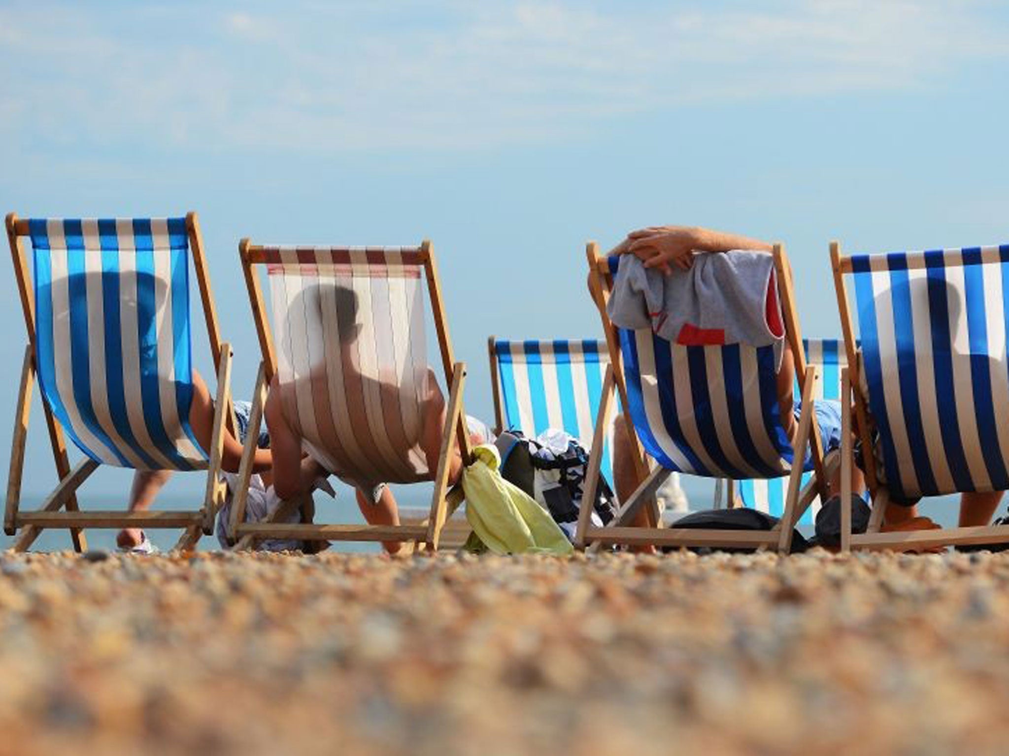 People relax in deck chairs during the hot weather on Brighton beach on 1 August, 2013