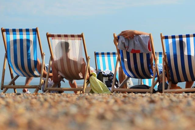 People relax in deck chairs during the hot weather on Brighton beach on 1 August, 2013