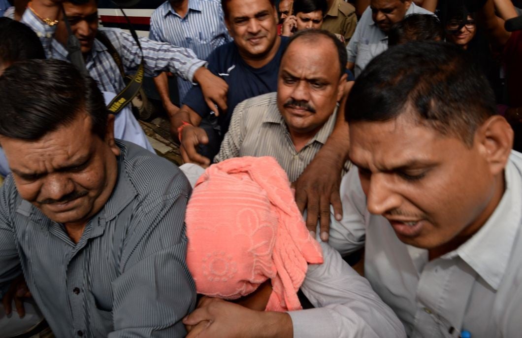Indian policemen escort the juvenile (C, in pink hood), accused in the December 2012 gang-rape of a student, to a court in New Delhi on August 31, 2013.