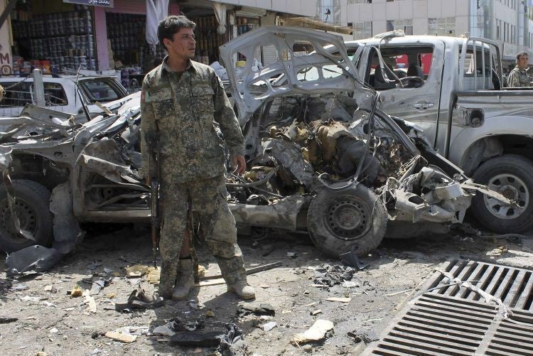 An Afghan security personnel inspects vehicle wreckage at the site of a suicide attack in Kandahar province 31 August 31, 2013. A suicide bomber detonated an explosive in an attack that killed 18