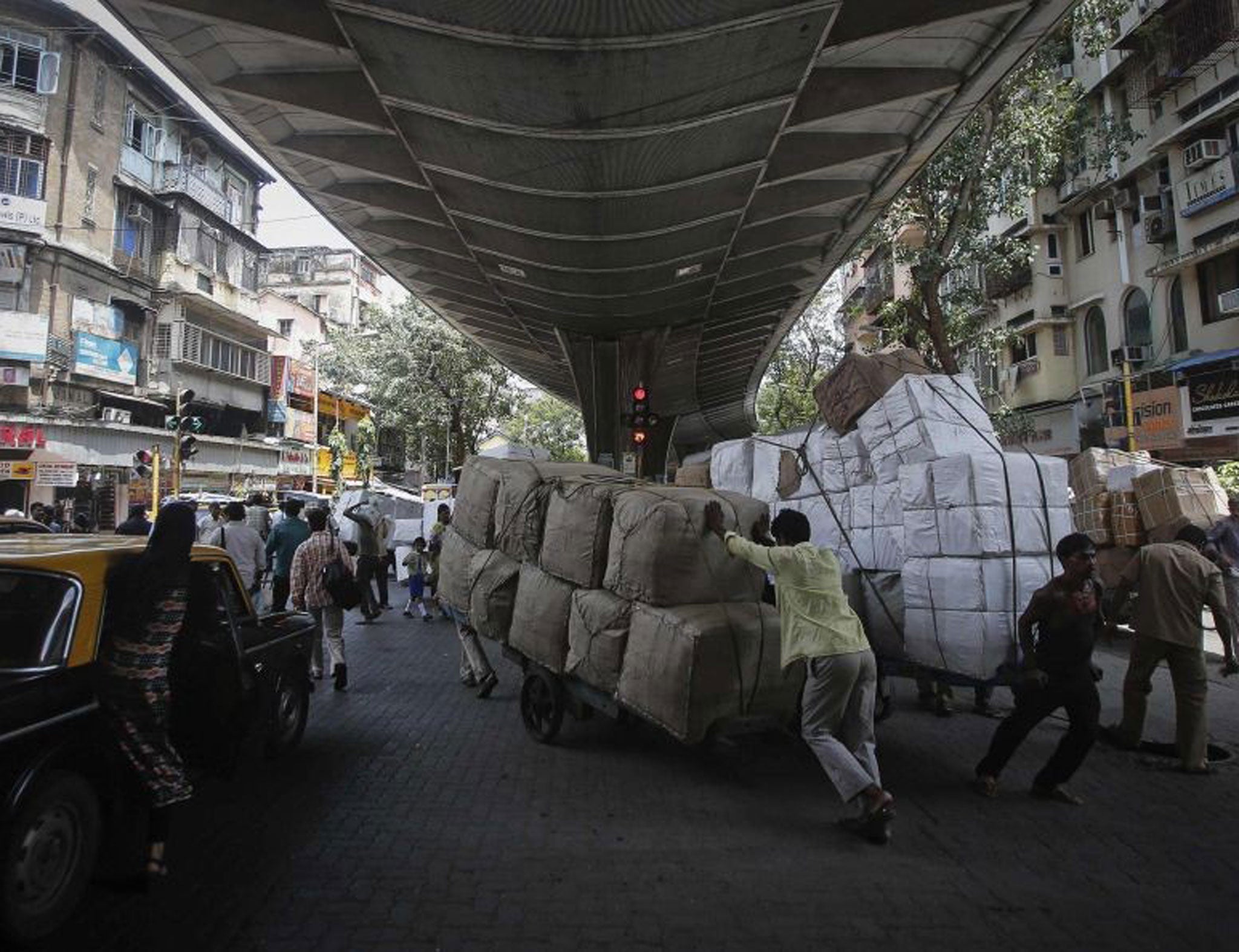 Laboueres move handcarts loaded with goods under a flyover at a market in Mumbai