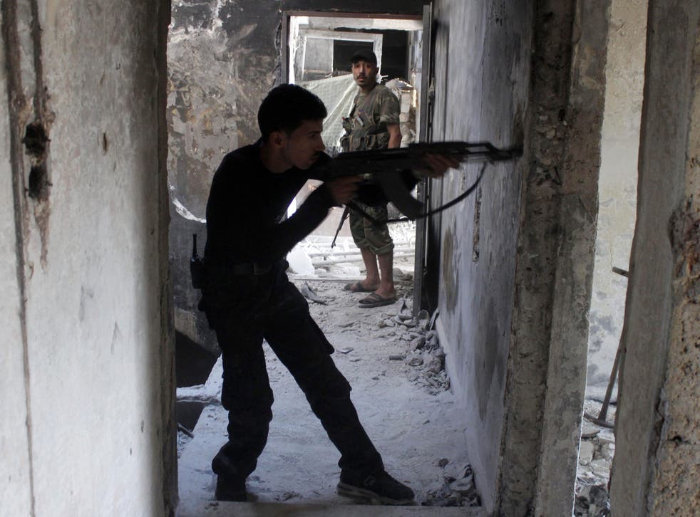 A Free Syrian Army fighter takes up a position inside a building as he points his weapon in the old city of Aleppo