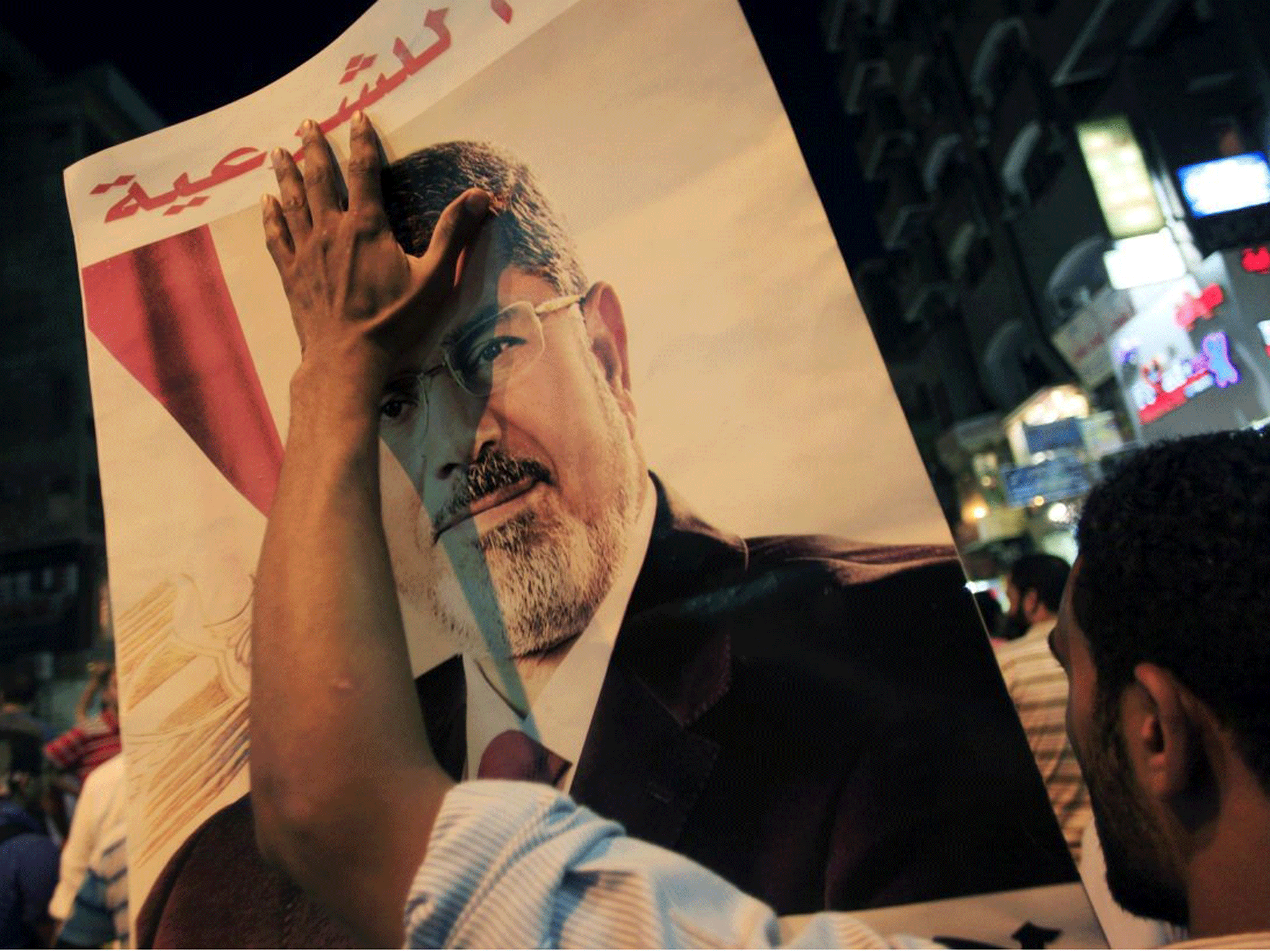 A supporter of ousted president Mohammed Morsi waves his picture to commemorate two months since leader was deposed
