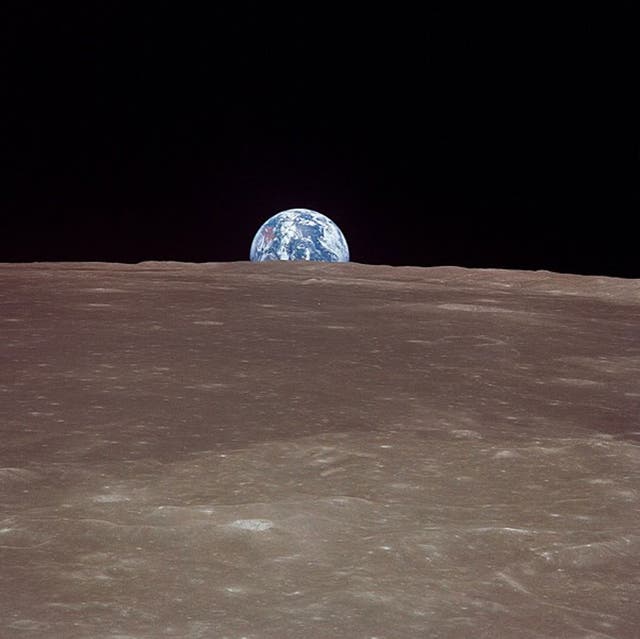 This image taken 20 July 1969 from Apollo 11 shows the Earth rising over the limb of the moon much as the Harvest Moon does from our planetary perspective. Over the stark, scarred surface of the moon, the Earth floats in the void of space, a watery jewel swathed in ribbons of clouds.