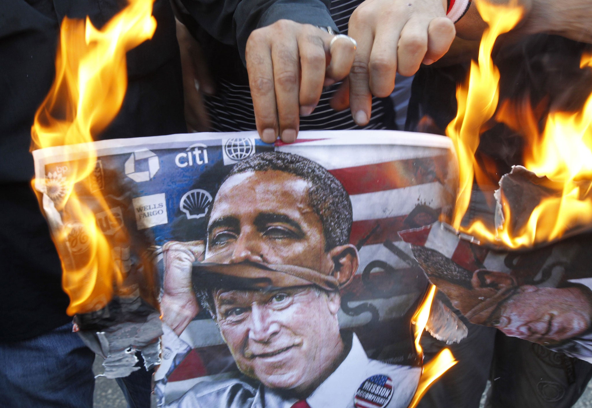 A pro-Assad protester near the US embassy in Beirut burns a poster superimposing Barack Obama on former President George Bush 