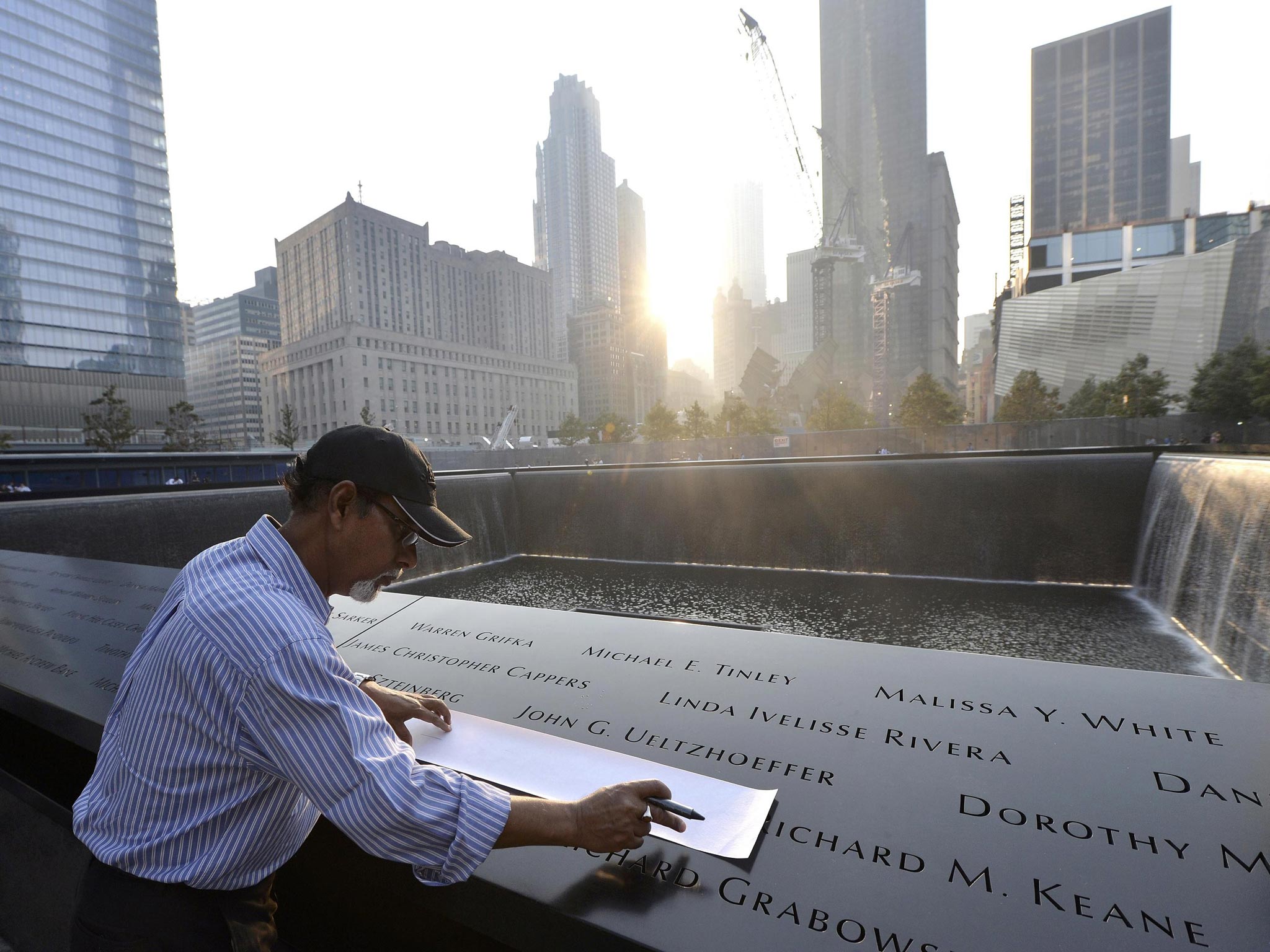 Wakiley Ramen Chowdhury of Chantilly, Virginia makes a rubbing of his niece's name, Shakila Yasmin, at the edge of the North Pool at the 9/11 Memorial during a ceremony marking the 12th anniversary of the 9/11 attacks on the World Trade Center in New York
