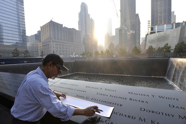 Wakiley Ramen Chowdhury of Chantilly, Virginia makes a rubbing of his niece's name, Shakila Yasmin, at the edge of the North Pool at the 9/11 Memorial during a ceremony marking the 12th anniversary of the 9/11 attacks on the World Trade Center in New York