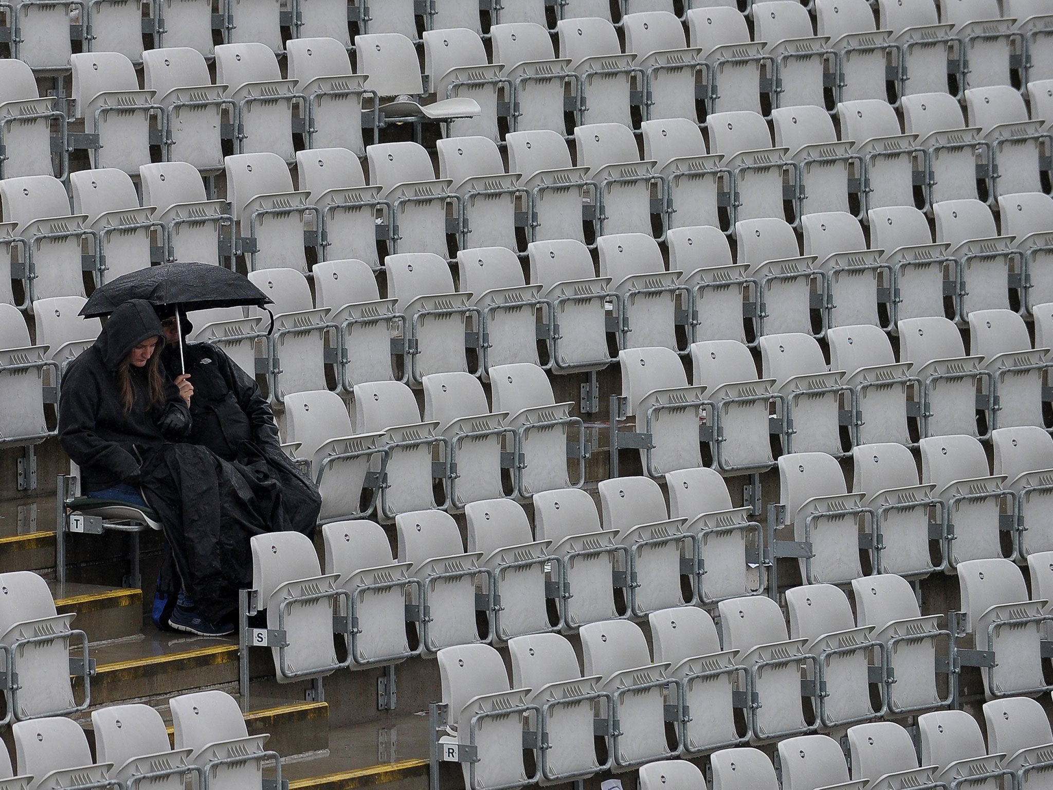 Fans wait in the rain as play is halted during the third one day international