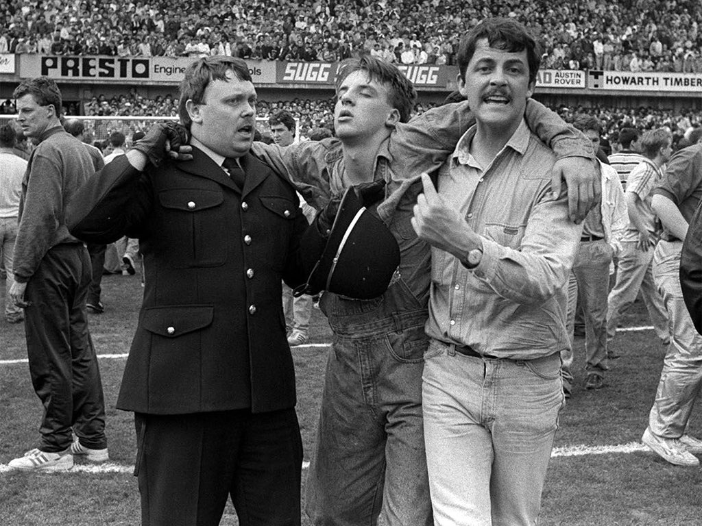 An injured fan gets help on the pitch, as disaster engulfs the FA Cup semi-final match on 15 April 1989