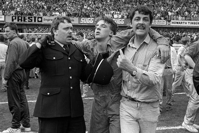 An injured fan gets help on the pitch, as disaster engulfs the FA Cup semi-final match on 15 April 1989
