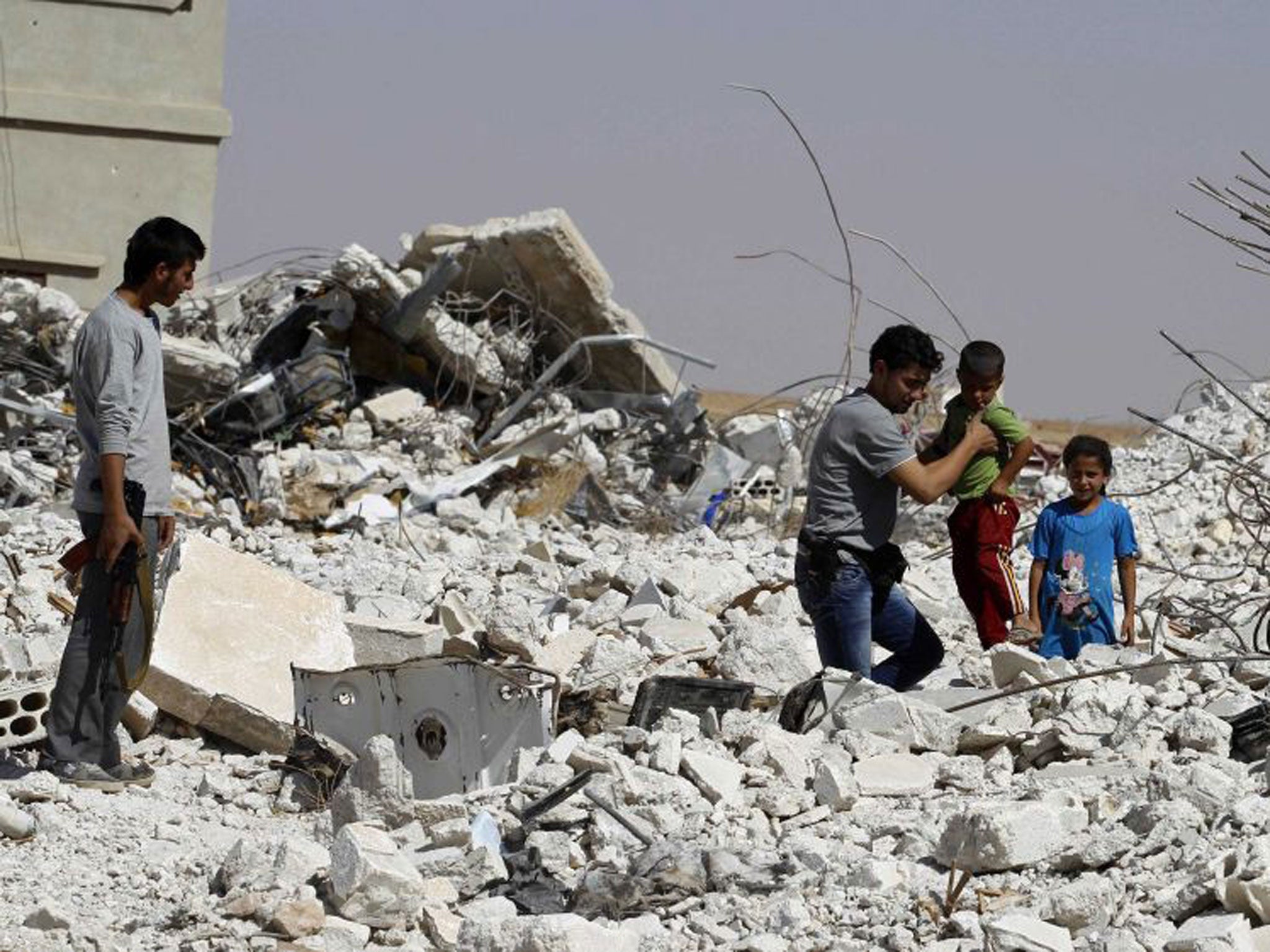 A man helps a boy through rubble in the eastern Hama countryside