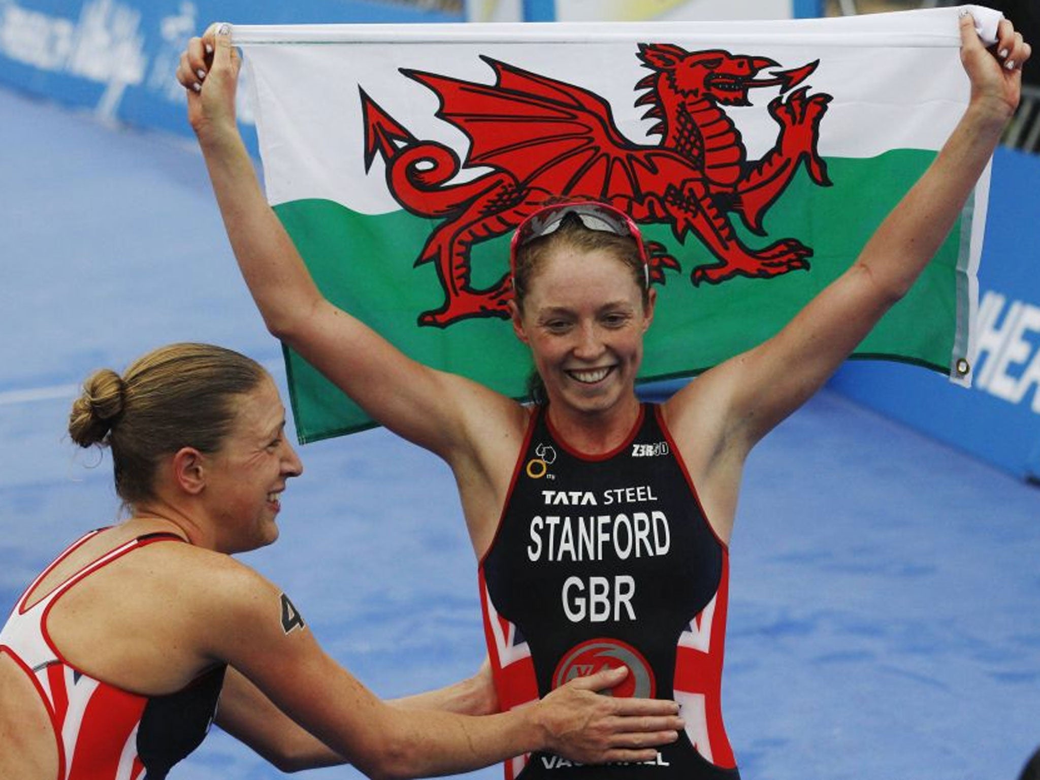 Golden girl: World champion Non Stanford raises the Welsh flag in triumph and gets a pat from silver medallist Jodie Stimpson