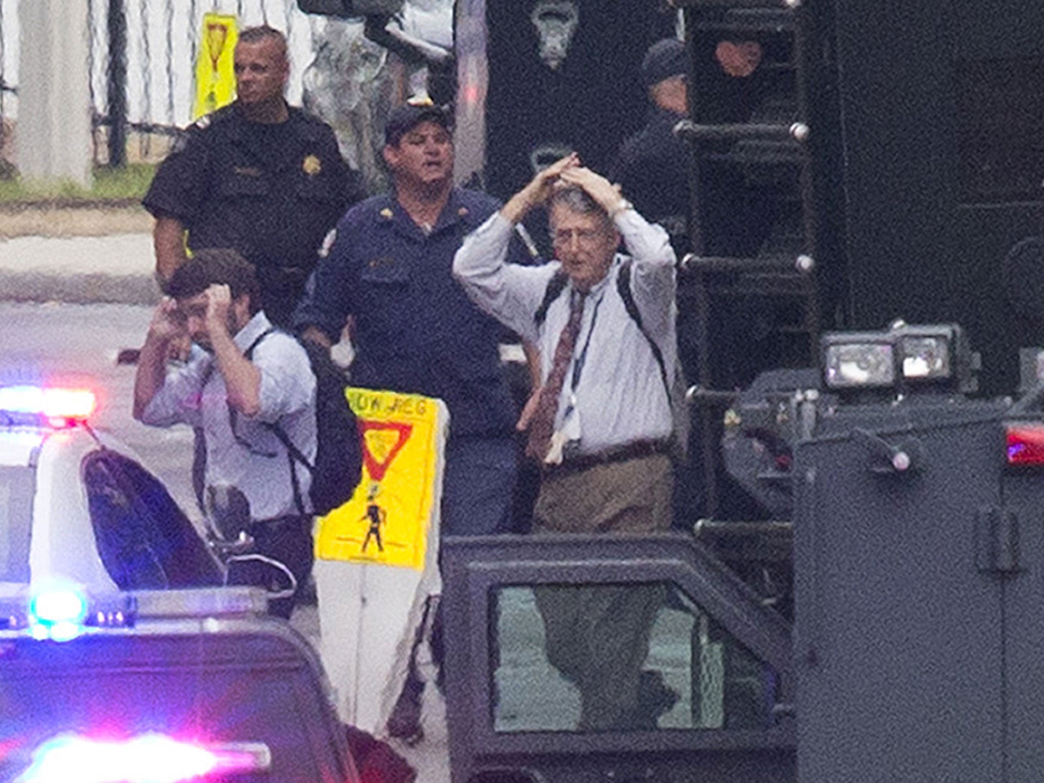 People hold their hands to their heads as they are escorted out of the building where a deadly shooting rampage occurred at the Washington Navy Yard in Washington