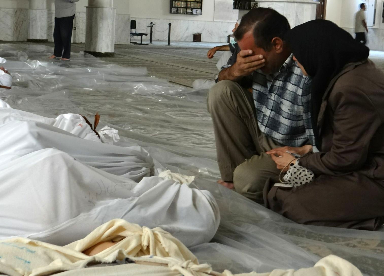 A Syrian couple mourn in front of bodies following what has now been confirmed by the UN as a toxic gas attack