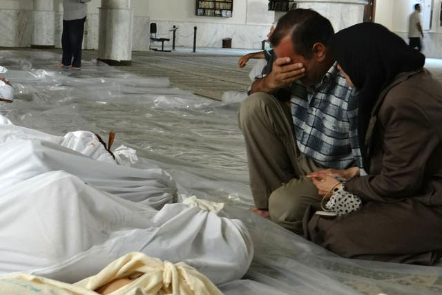 A Syrian couple mourn in front of dead bodies