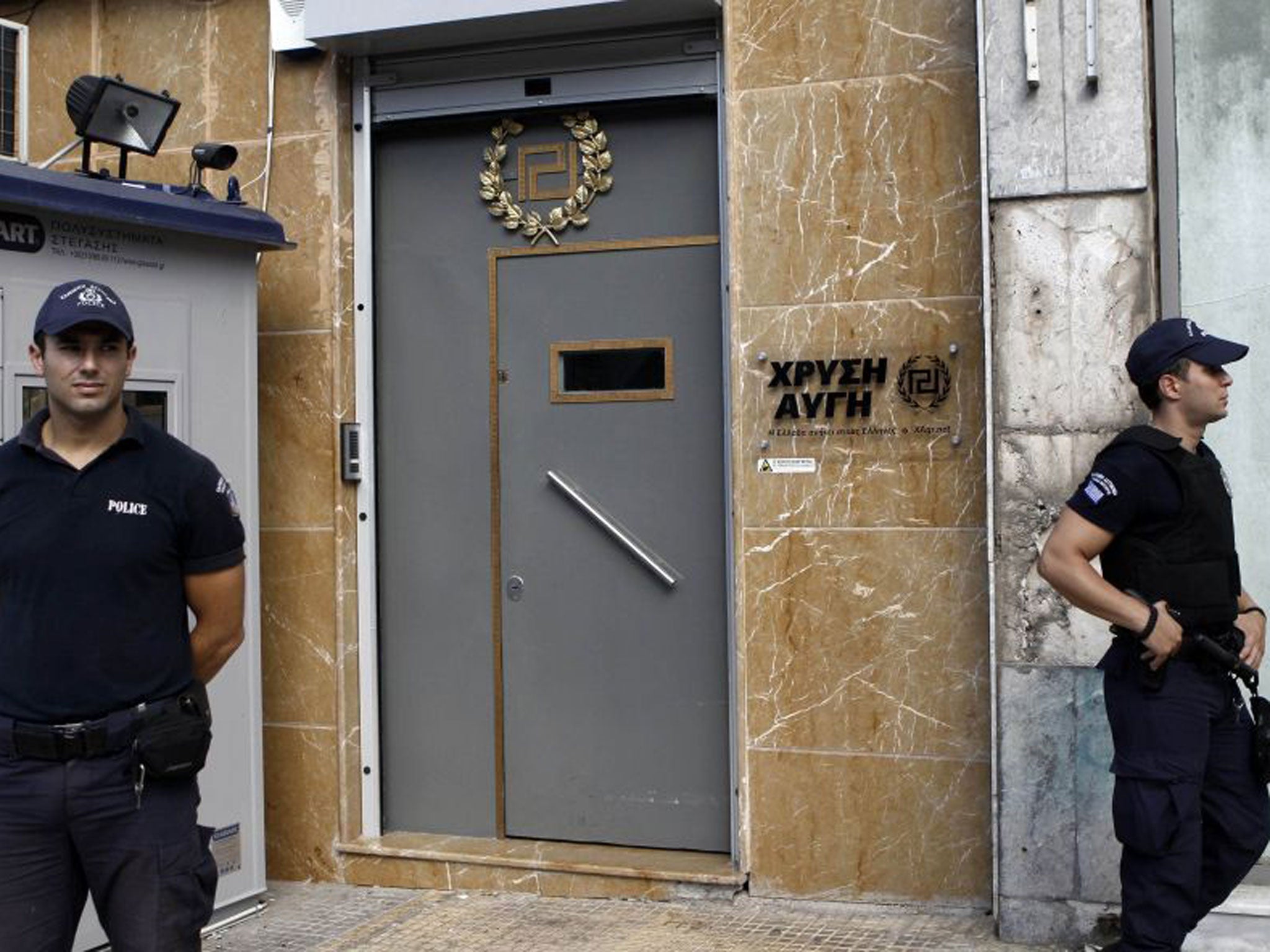 Police officers stand guard outside the headquarters of the Golden Dawn far-right party in Athens