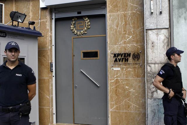 Police officers stand guard outside the headquarters of the Golden Dawn far-right party in Athens