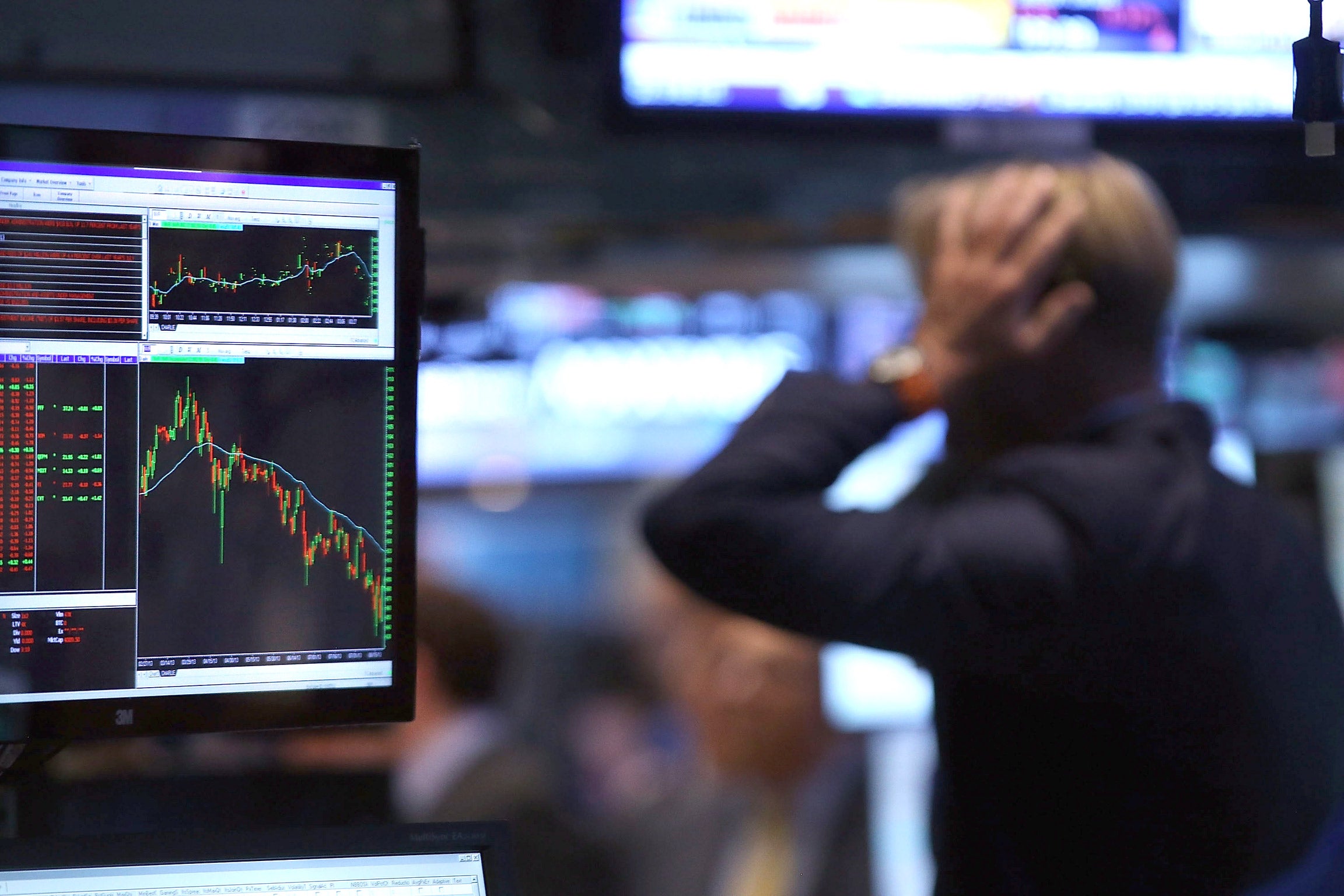 A trader at the New York Stock Exchange puts his hand to his head