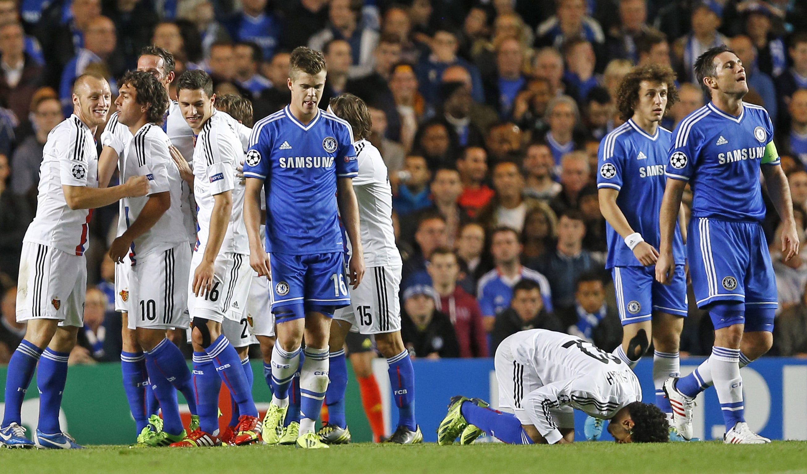 Chelsea players look dejected following a rare home defeat; meanwhile Basel celebrate