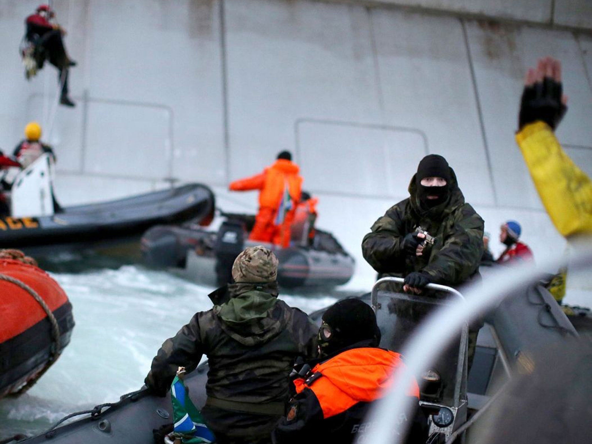 Greenpeace took this photo of a camouflaged officer from the Russian Coast Guard pointing a gun at an activist during an attempt to scale an Arctic oil rig on Wednesday