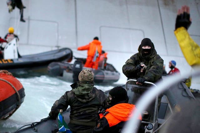 Greenpeace took this photo of a camouflaged officer from the Russian Coast Guard pointing a gun at an activist during an attempt to scale an Arctic oil rig on Wednesday