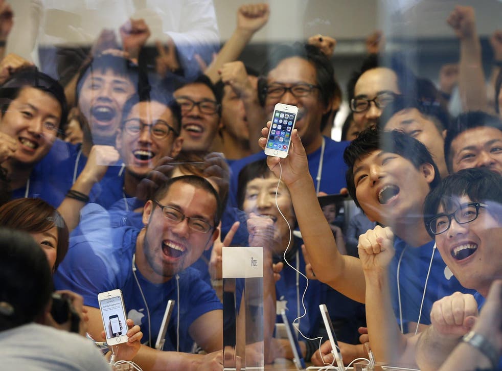 Apple store staff pose with the new Apple iPhone 5S before its goes on sale at an Apple Store at Tokyo's Ginza shopping district