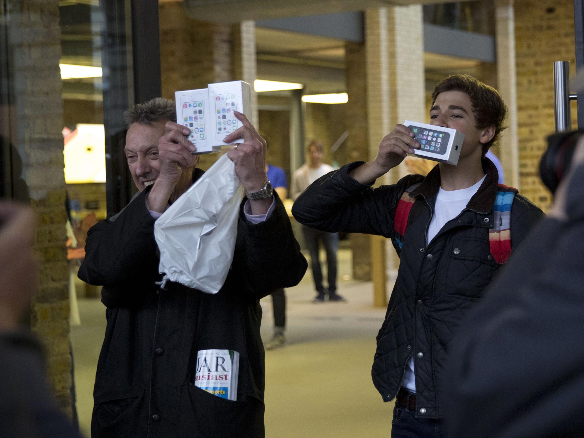 Norman Hicks, left, and Jess Green, aged 15, the first two customers at the front of the queue, pose for photographers with boxed iPhone 5s handsets as they leave the Apple Store in Covent Garden, London