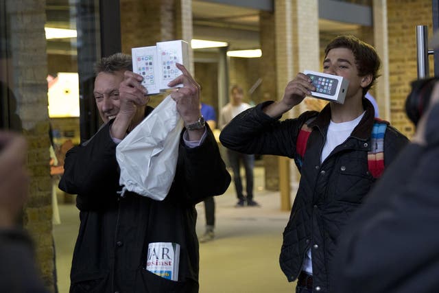 Norman Hicks, left, and Jess Green, aged 15, the first two customers at the front of the queue, pose for photographers with boxed iPhone 5s handsets as they leave the Apple Store in Covent Garden, London
