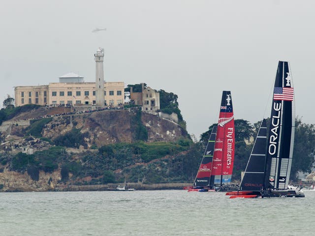 Passing Alcatraz Island in light wind, Emirates Team New Zealand and Oracle Team USA sail America's Cup race 13