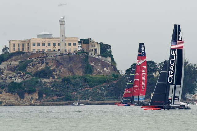 Passing Alcatraz Island in light wind, Emirates Team New Zealand and Oracle Team USA sail America's Cup race 13