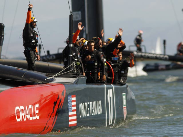 Crew members from Team USA wave to the crowd after defeating Emirates Team New Zealand during Race 15 in the 34th America's Cup yacht sailing race in San Francisco, California