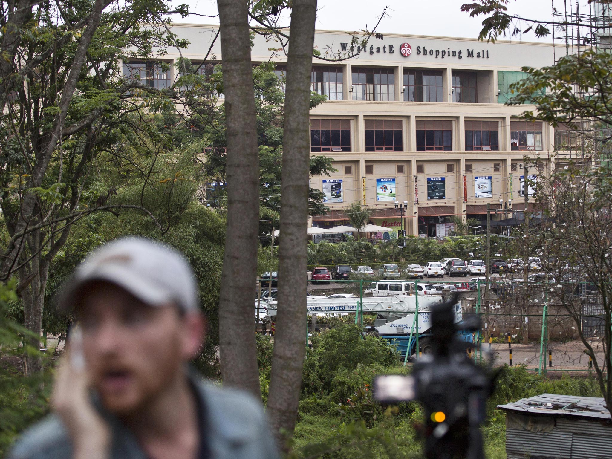 A reporter films while a bout of heavy gunfire takes place shortly after dawn at the Westgate Mall in Nairobi, Kenya