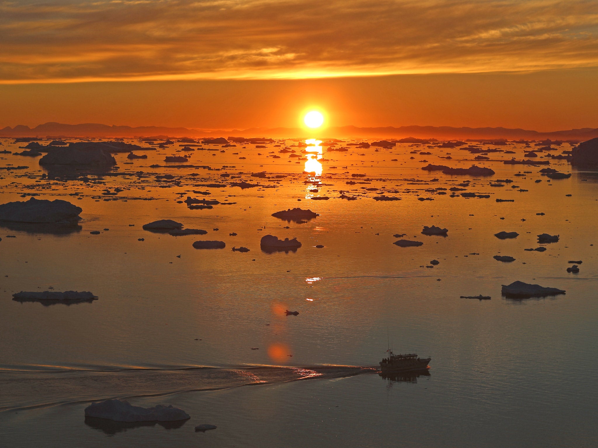 The sun sets over icebergs near Ilulissat in Greenland