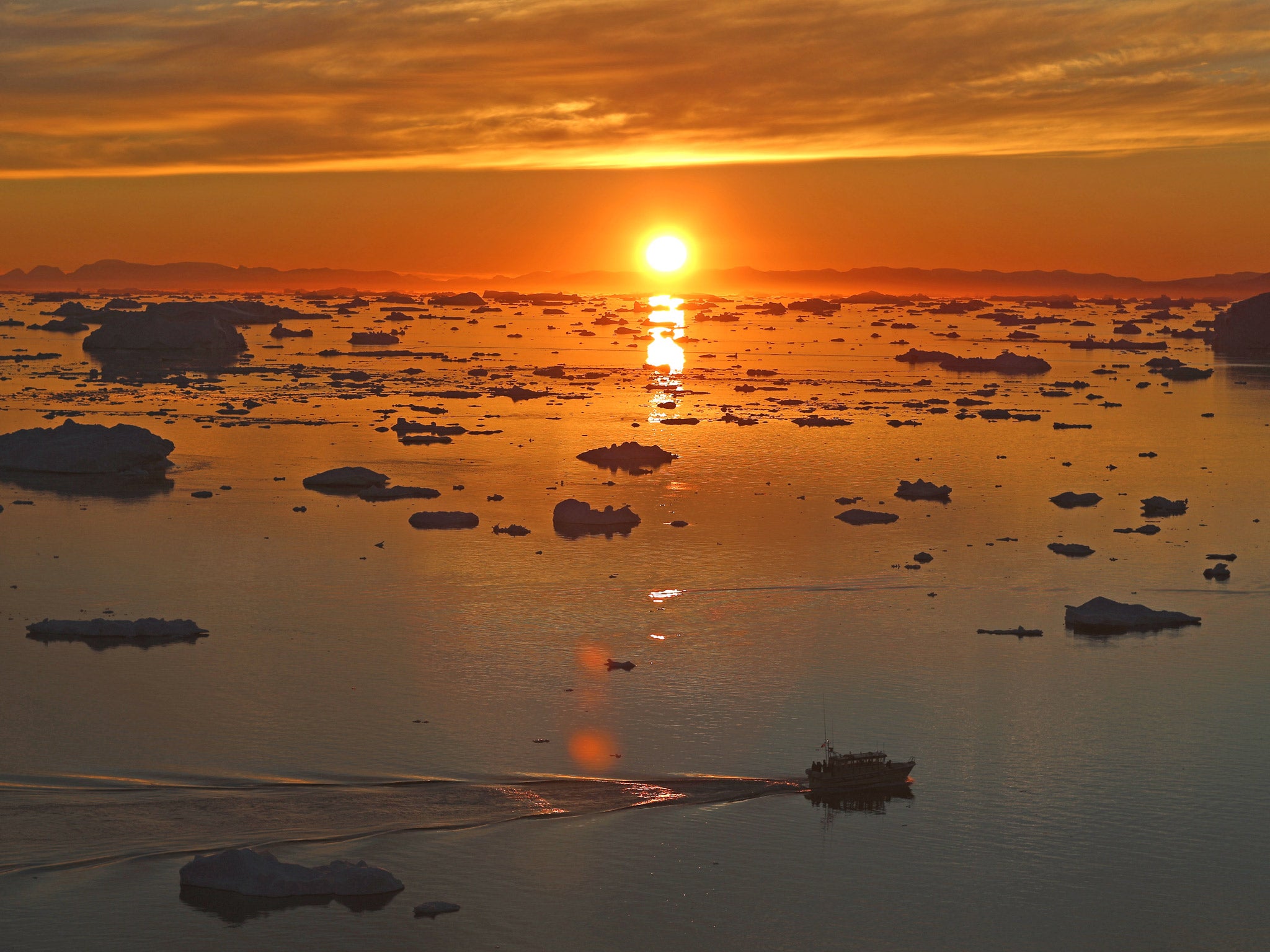 A boat is seen seen among the icebergs that have broken off from the Jakobshavn Glacier in Ilulissat, Greenland