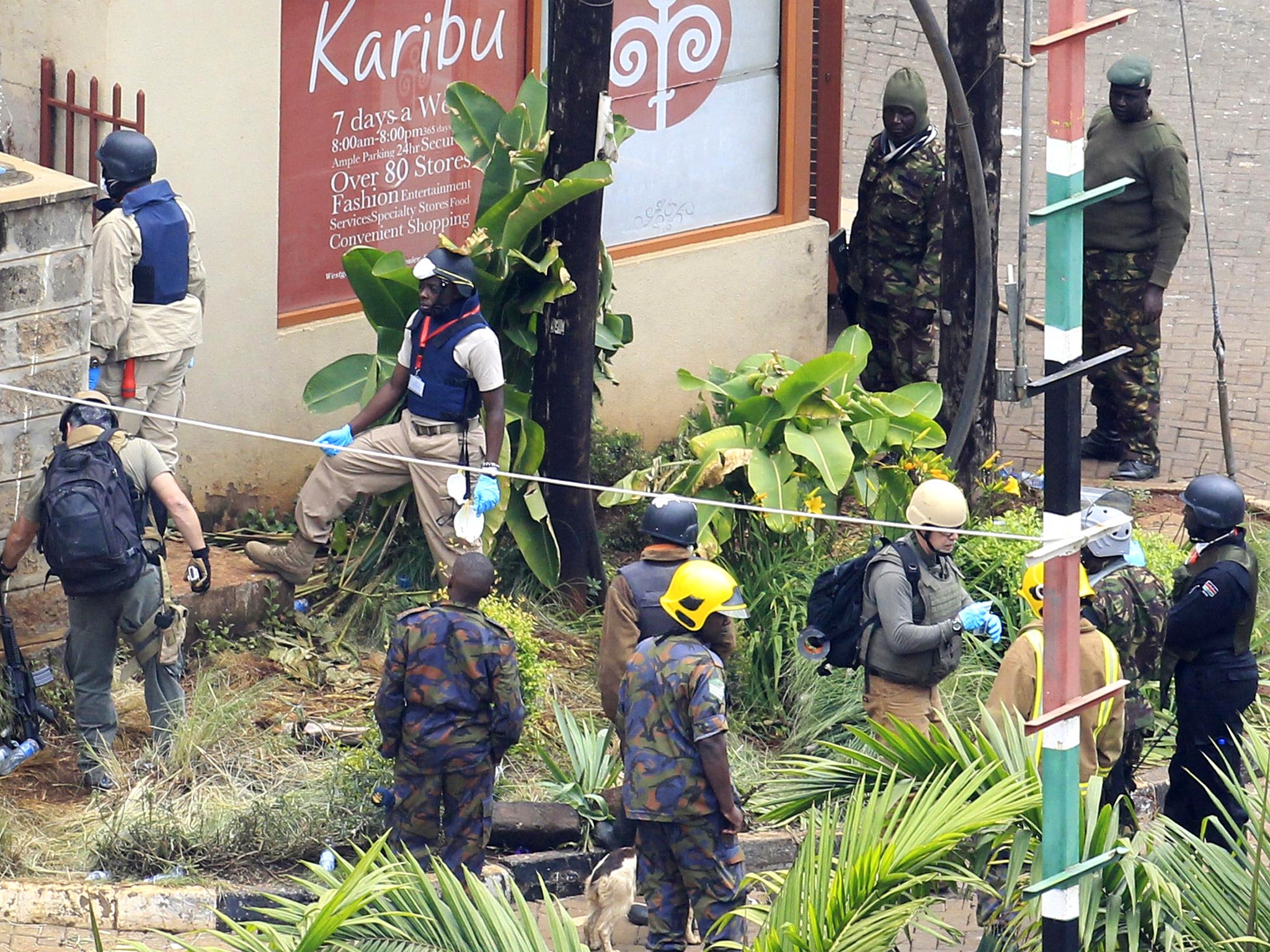 Foreign forensic experts, flanked by Kenyan military personnel, check the perimeter walls around Westgate shopping mall