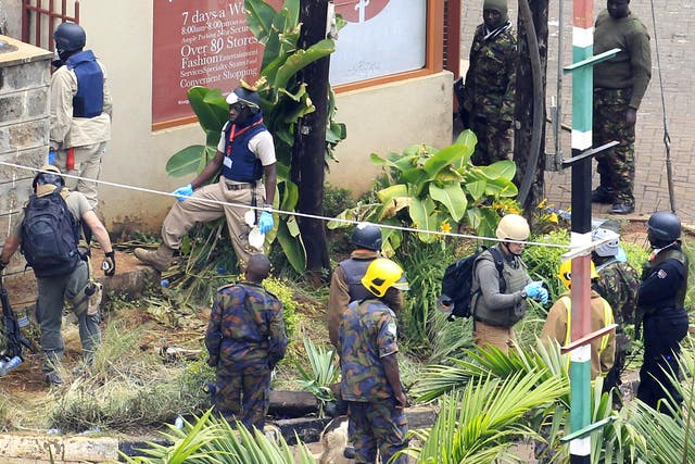 Foreign forensic experts, flanked by Kenyan military personnel, check the perimeter walls around Westgate shopping mall