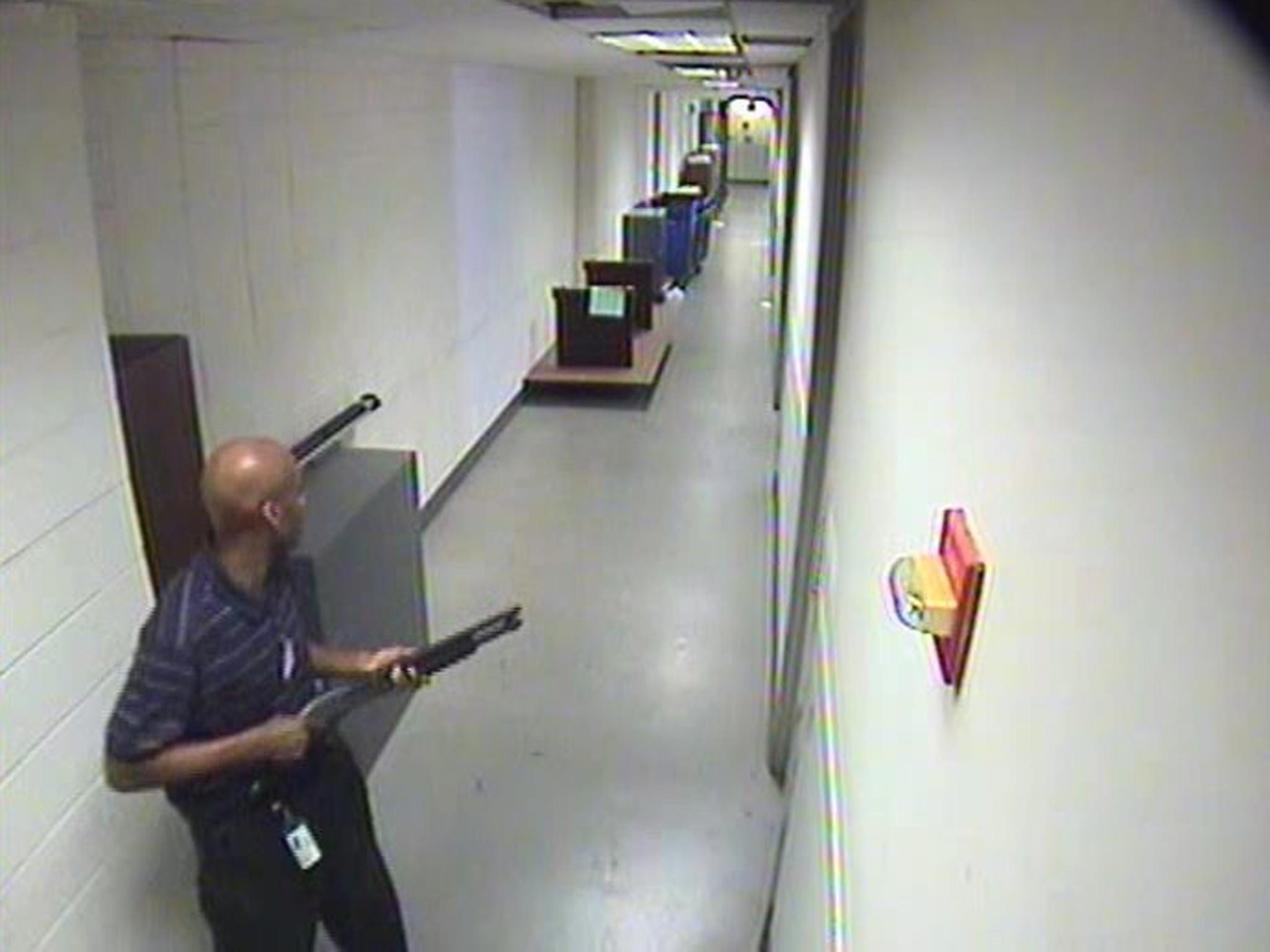 A handout surveillance image released by the Federal Bureau of Investigation (FBI) on 25 September 2013 showing Aaron Alexis in the hallway of building #197 carrying a Remington shotgun as his rampage began in Washington