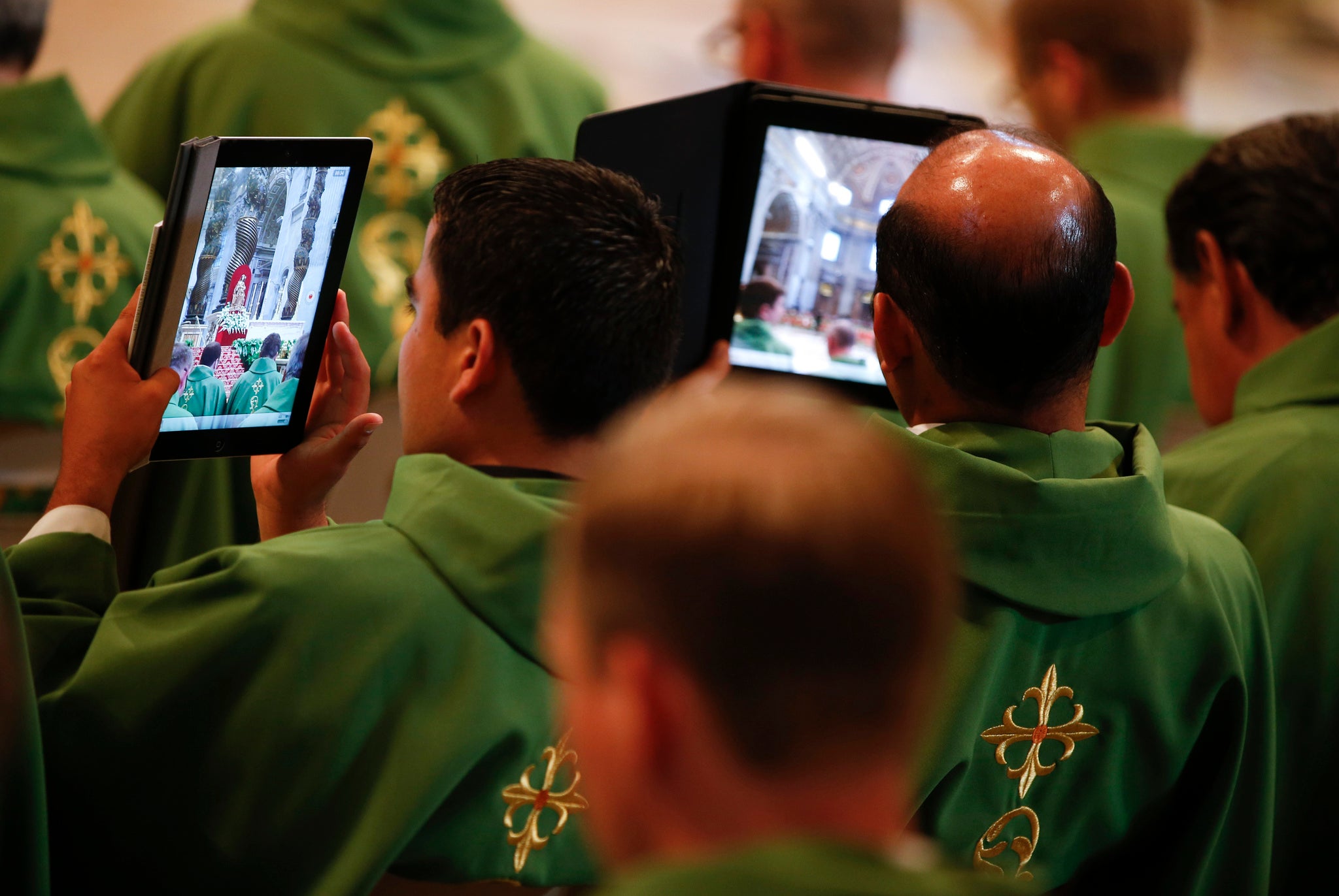 Priests take pictures with tablets as Pope Francis leads a mass in Saint Peter's Basilica at the Vatican July 7, 2013.