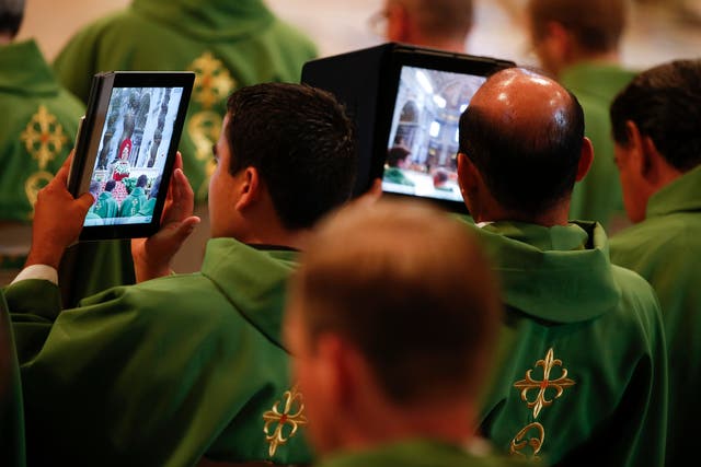 Priests take pictures with tablets as Pope Francis leads a mass in Saint Peter's Basilica at the Vatican July 7, 2013.