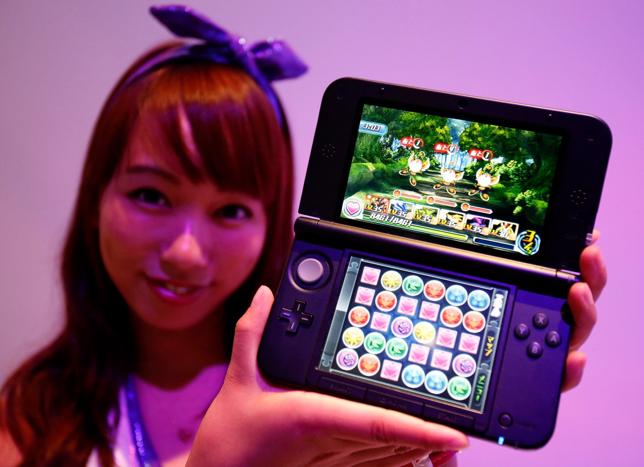 A booth girl holds a Nintendo 3DS displaying GungHo Online Entertainment Inc's new game "Puzzle & Dragons Z" at the Tokyo Game Show in Chiba, east of Tokyo September 19, 2013.