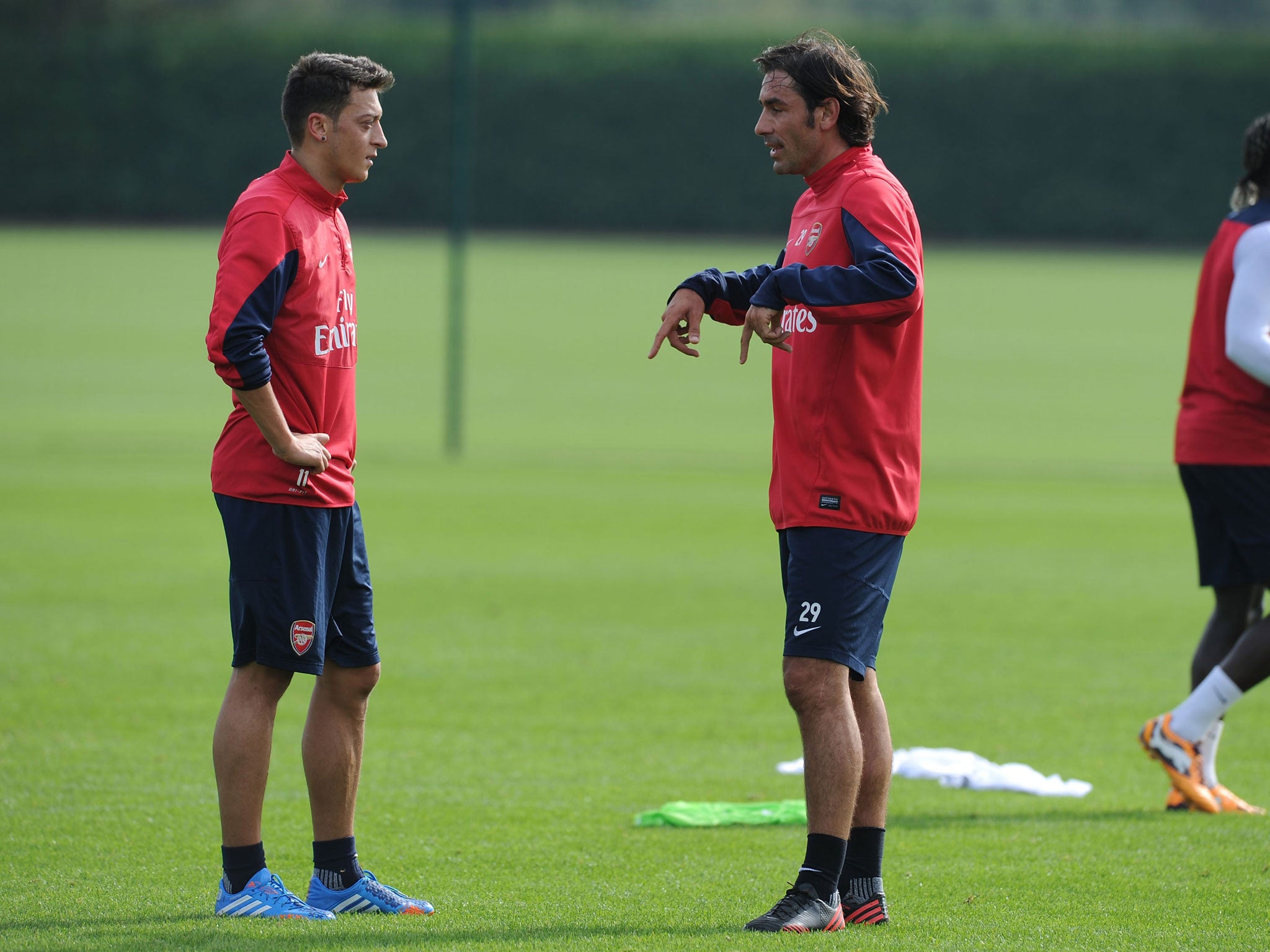 Mesut Ozil listens as Robert Pires gives the Arsenal man some advice