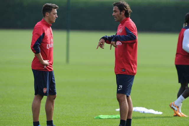 Mesut Ozil listens as Robert Pires gives the Arsenal man some advice