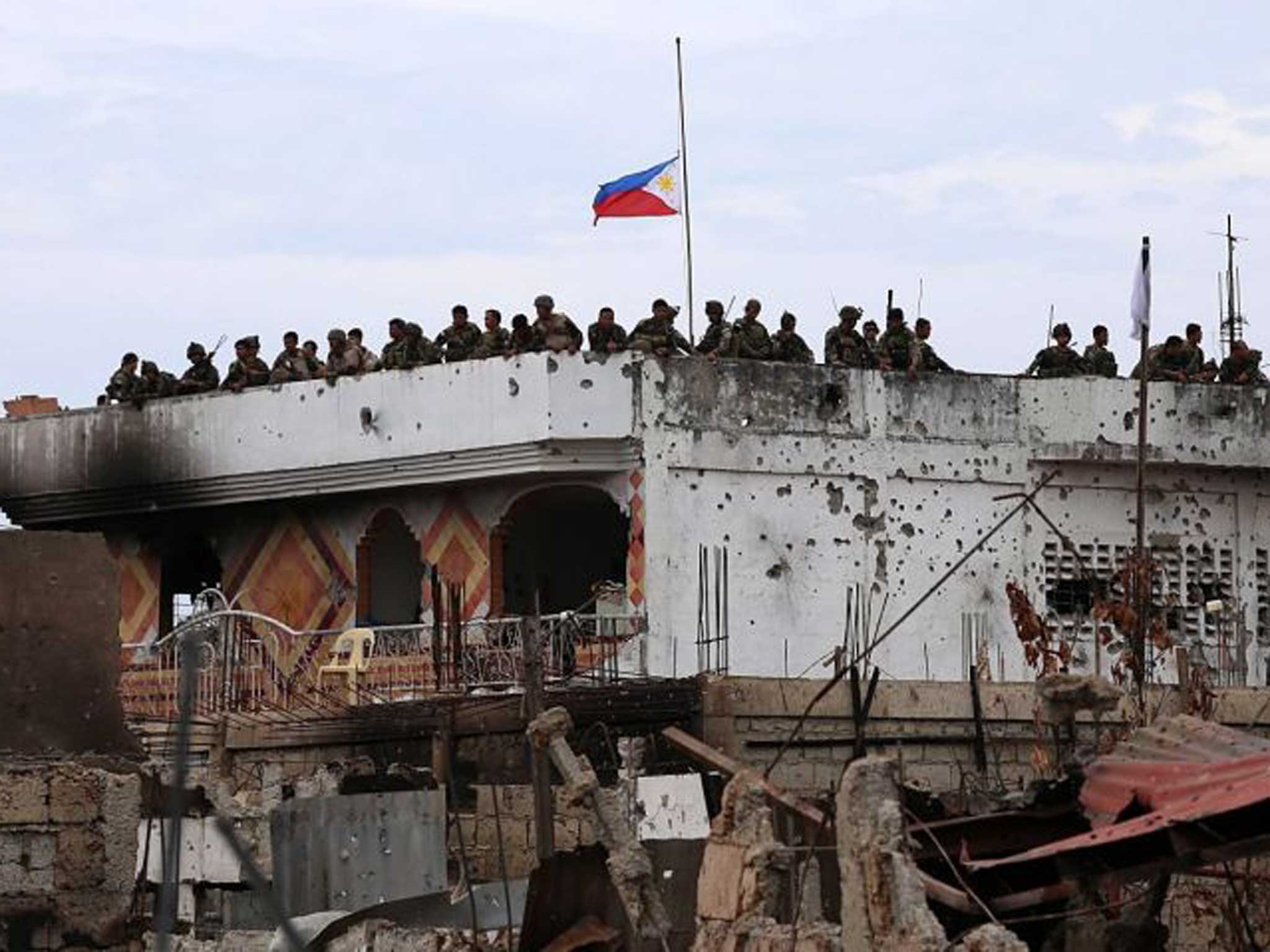 The flag of the Philippines flies at half-mast while soldiers secure the site controlled by rebels in the residential village in Zamboanga city, southern Philippines