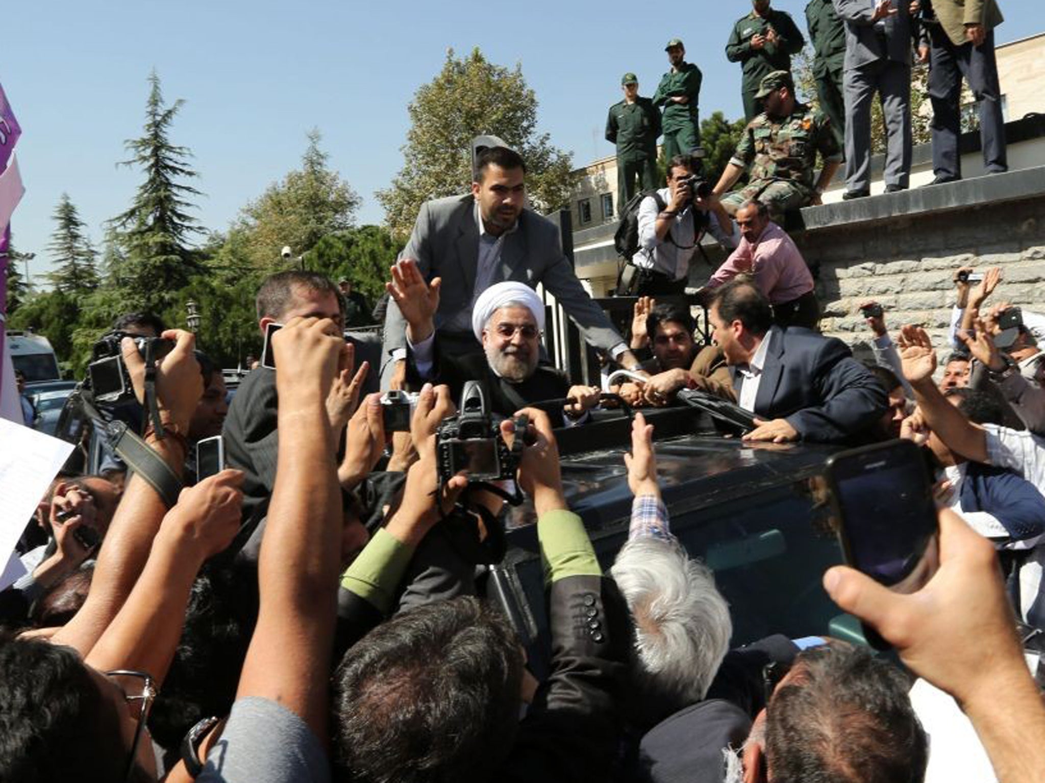 Iranian president Hassan Rouhani is surrounded by bodyguards as he arrives at Tehran's Mehrabad Airport