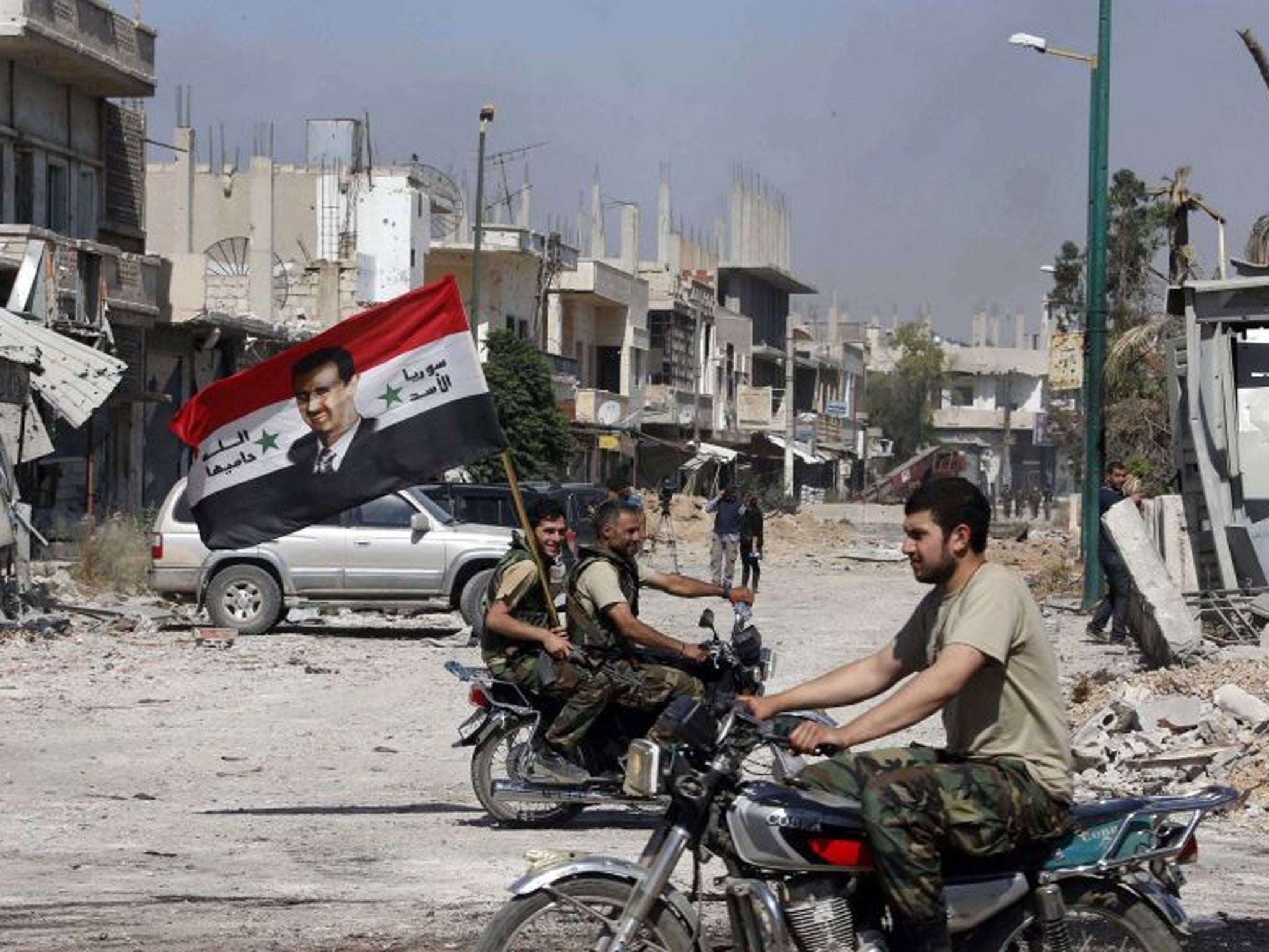 Flying the flag: Forces loyal to President Assad celebrate as the Syrian army take control in Qusair in June