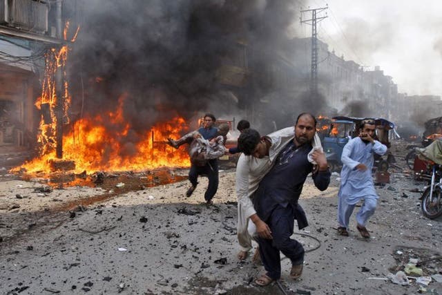Injured Pakistani men are carried away from the site of a blast shortly after a car explosion in Peshawar, 29 September