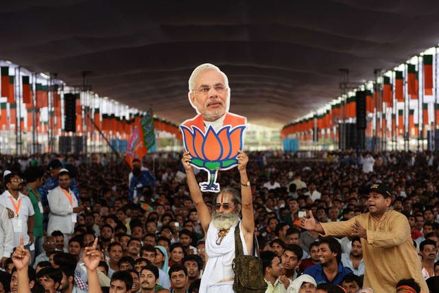 A supporter of the BJP holds a cutout of Narendra Modi during the election rally in New Delhi