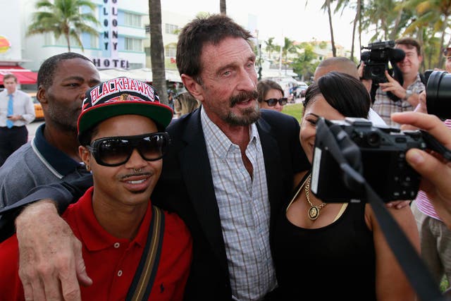 Computer software pioneer John McAfee (C) poses with tourists as he speaks with reporters outside his hotel in Miami Beach, Florida December 13, 2012.
