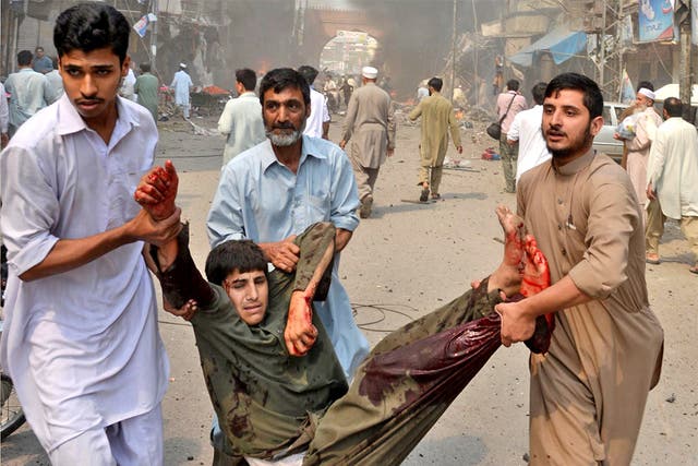 A blast victim is carried from the scene of a bomb explosion in the busy Kissa Khwani market in Peshawar, on September 29
