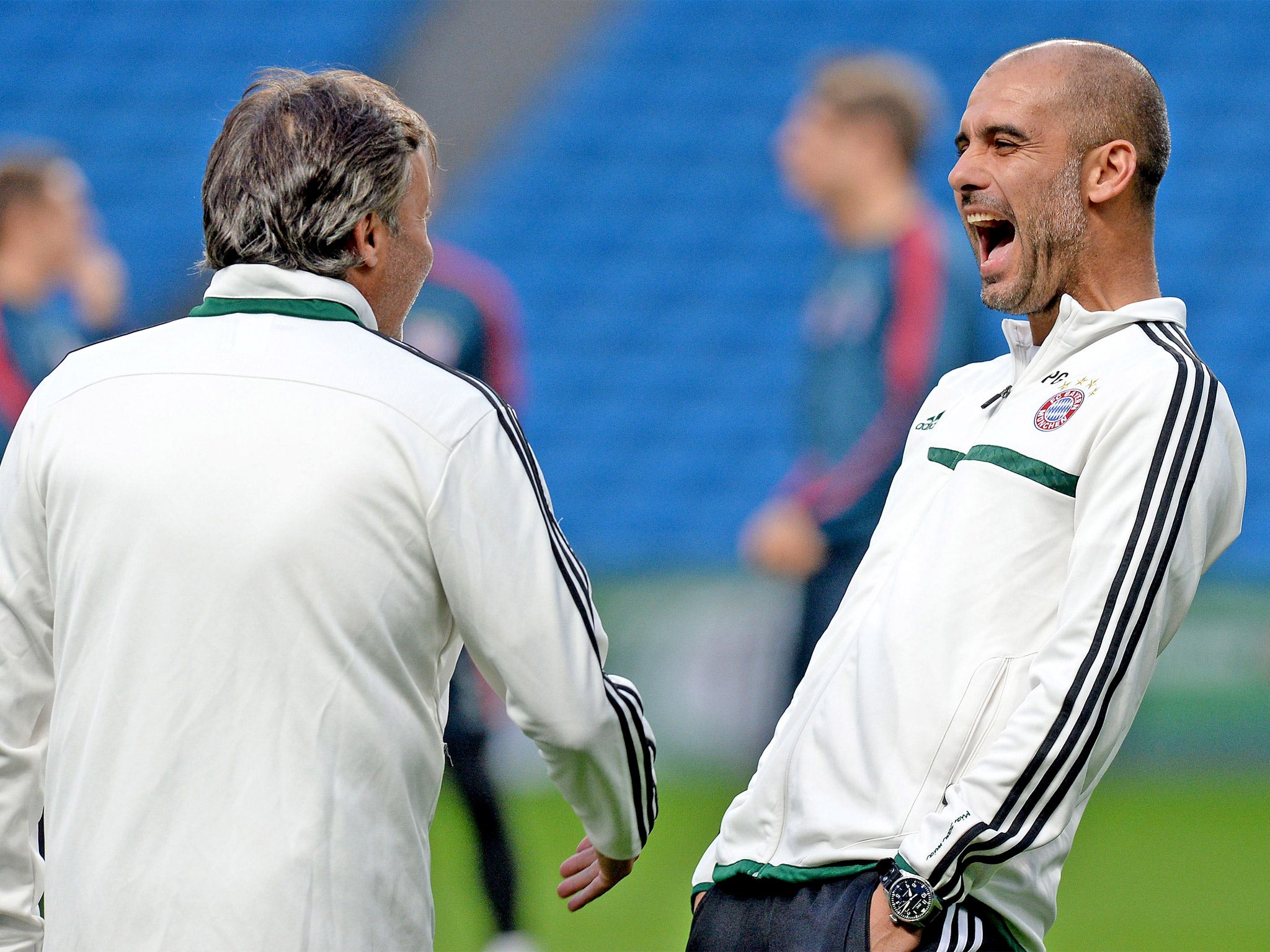 Pep Guardiola shares a joke with one of his coaches during training at the Etihad Stadium